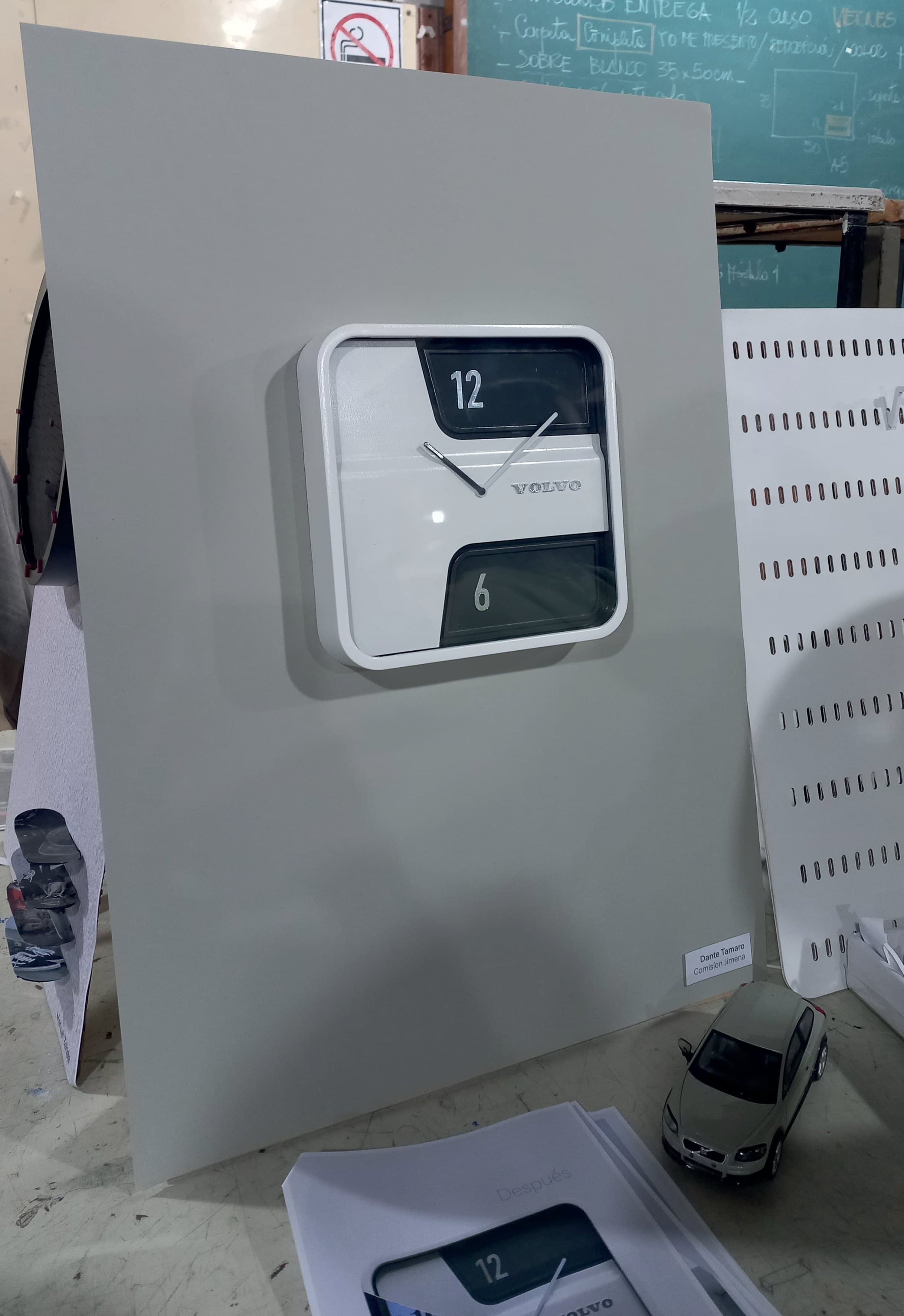 The physical model of the clock mounted on a grey presentation panel in the workshop.