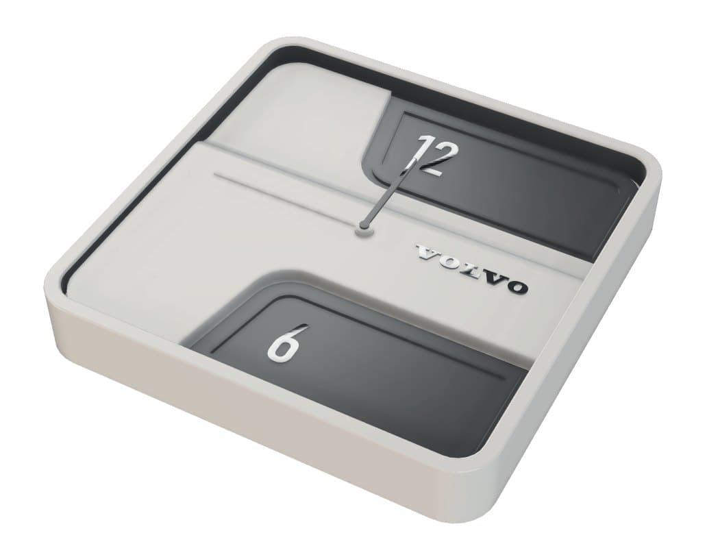 The redesigned clock in three-quarter view: cream body, two raised windows showing the 12 and the 6, and the Volvo wordmark debossed into the case.